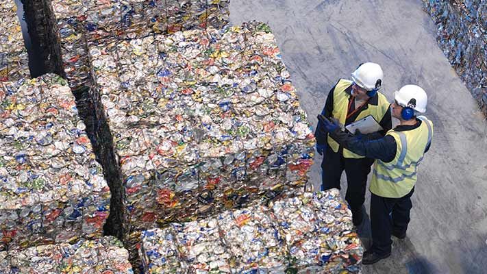 Overhead view of compacted trash with two workers in hard hats and reflective vests
