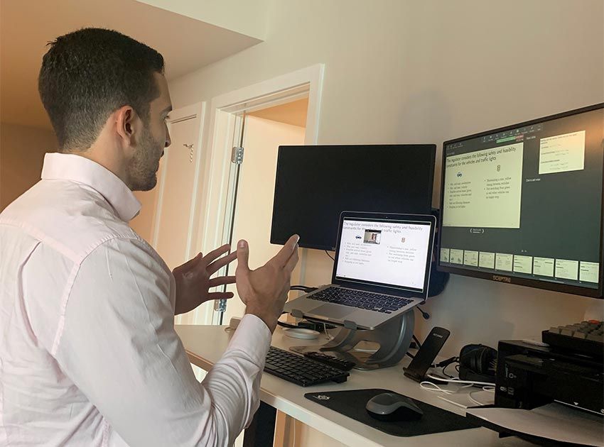 Man at standing desk with laptop and two monitors